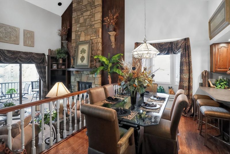 Dining table set for six beside the kitchen with wooded views and a chandelier