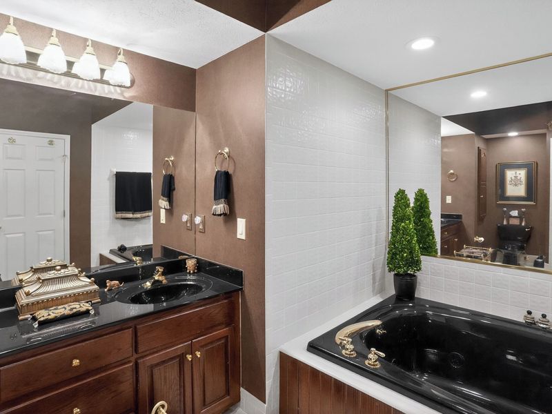 King suite bathroom with a 2-person whirlpool (Jacuzzi) tub and dark granite vanity