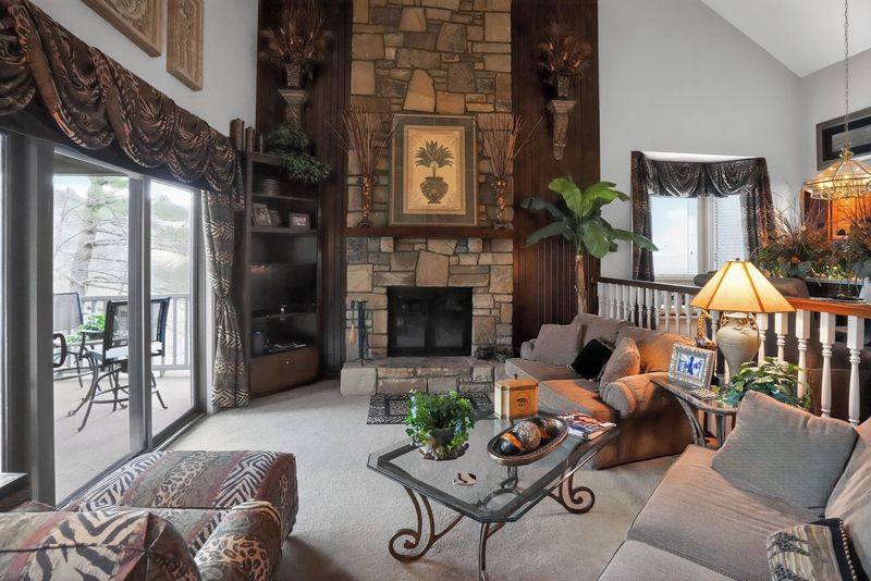 Floor-to-ceiling stone wood-burning fireplace with leather sofas and sliding doors to the balcony